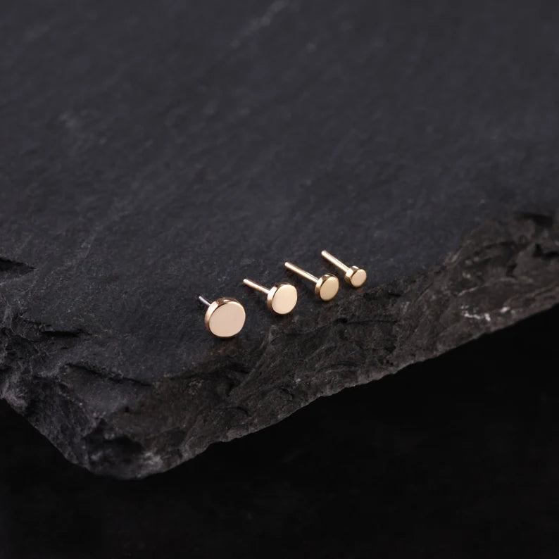 Choice of 14K gold stud earrings display on a dark stone surface
