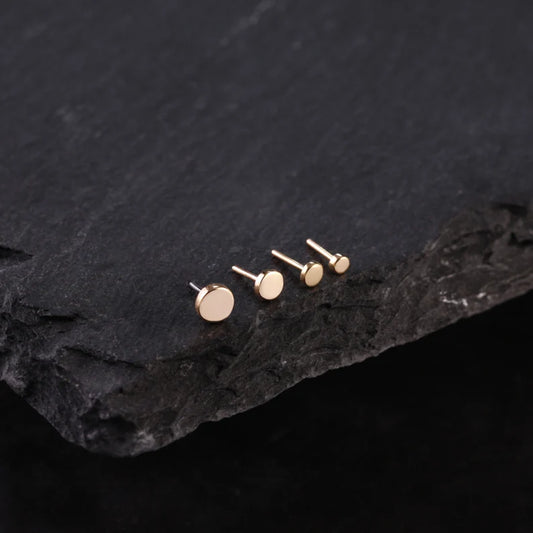 Choice of 14K gold stud earrings display on a dark stone surface