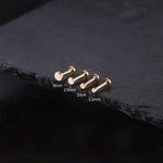 Gold bar earrings on a dark stone surface with size labels.