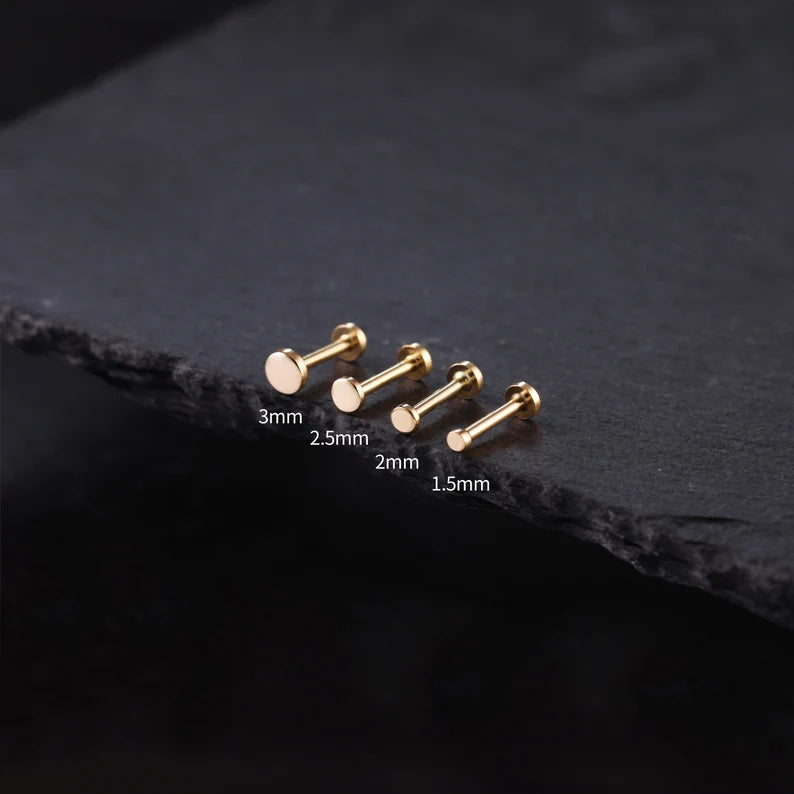 Gold bar earrings on a dark stone surface with size labels.