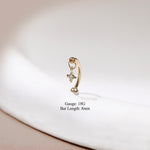 A gold huggie hoop earring with a dangling star charm set with a clear gemstone, displayed on a white textured surface with text overlay detailing the gauge and bar length.