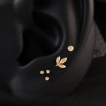 Gold leaf and dot earrings on a black ear lobe