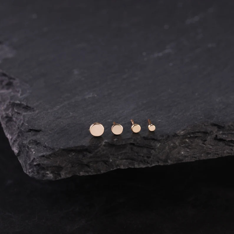 Set of gold stud earrings on a dark stone surface