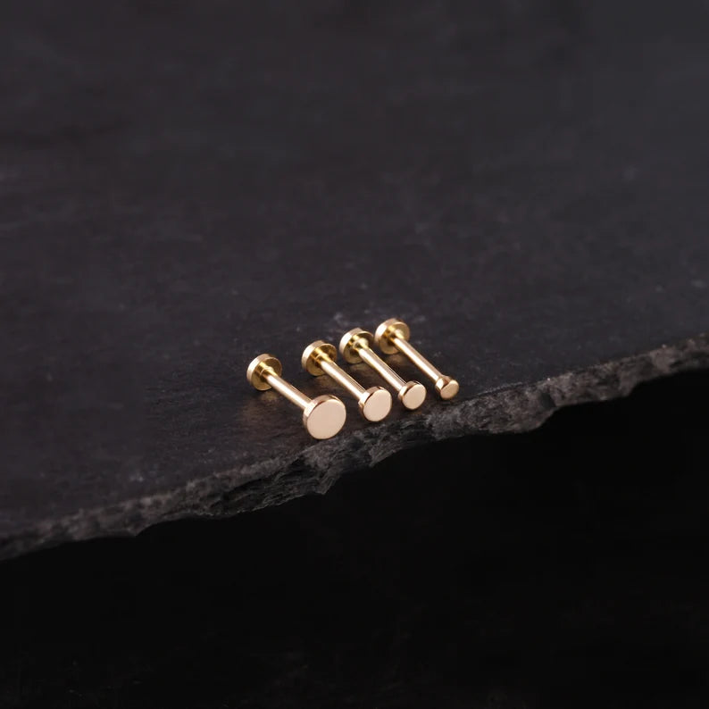Set of gold earrings on a dark stone surface