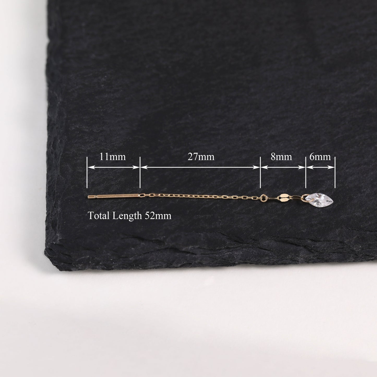 A gold-toned chain earring with a clear faceted stone, shown on a dark slate background with measurement annotations indicating a total length of 52mm.