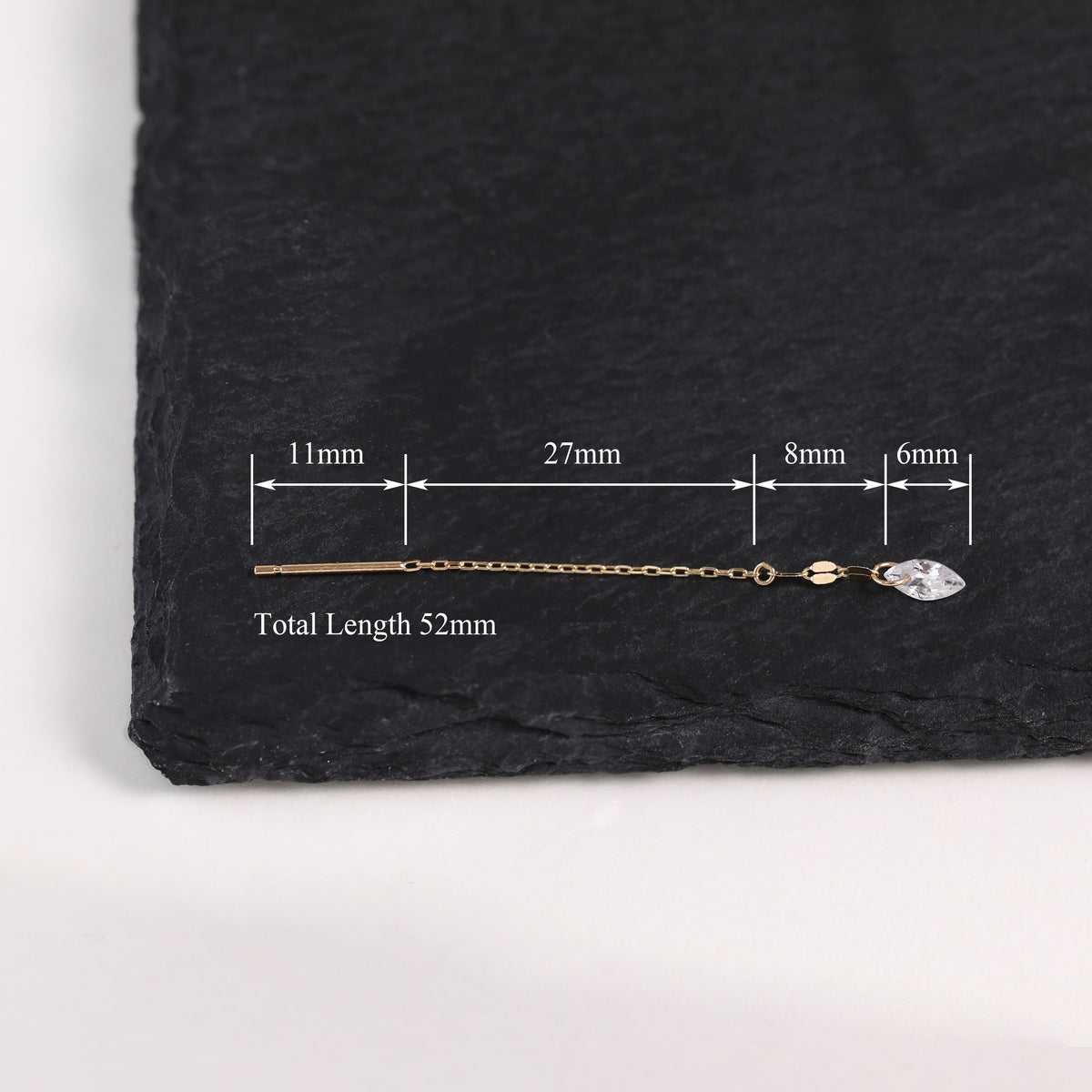 A gold-toned chain earring with a clear faceted stone, shown on a dark slate background with measurement annotations indicating a total length of 52mm.